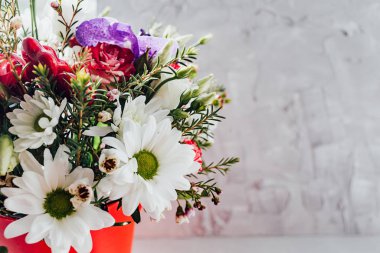 Gri bir duvarın arkasında farklı taze çiçeklerden oluşan güzel bir buket. Dalların eklendiği bir buket. Boşluğu kopyala.