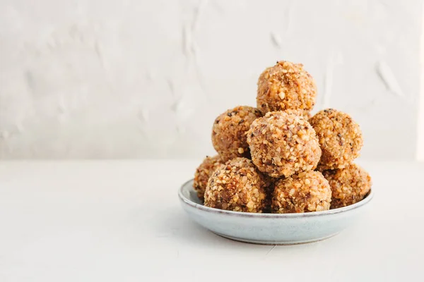 Homemade healthy organic protein energy bites with nuts, dates, banana, coconut oil and honey. Sports food, vegetarian raw snack on a grey background. Close-up, copy space.