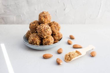 Organik sağlıklı enerji topları, fıstık, bal, arka planda ceviz parçacıkları, boşluğu kopyala, düz uzan. Sağlıklı yemek, sağlıklı atıştırmalık. Çiğ tatlı. Gri arkaplan.