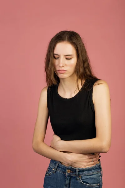 Portrait of attractive lovely girl holds her stomach having gastritis on bright pink color background. Gastrointestinal tract diseases. Frustrating health problems