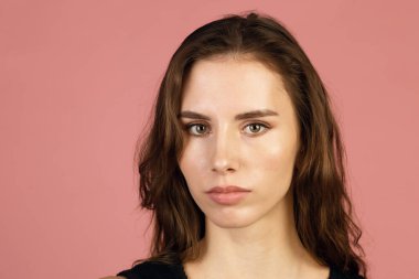 Ciddi görünen bir kadının fotoğrafı, önemli bir şey hakkında düşünüyor, stüdyoda duruyor. Yüz ifadesi. Pembe arkaplan.