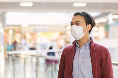 Koruyucu maskeli beyaz bir adamın portresi bir alışveriş merkezinde halka açık bir yere bakıyor. Koronavirüs ve pandemiden gelen sağlık ve güvenlik hayatı kavramı. Metin için boşluk