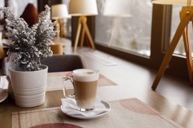 Cafe 'deki masaya sıcak latte içeceği. Büyük, berrak bir bardakta kahve içmek. Düz beyaz ya da sütlü kahve. Hipster kahve dükkanı..