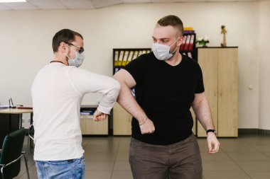 Coronavirus 'un (COVID-19) yayılmasını önlemek için dirsek seği selamı. İki insan sarılmak ya da tokalaşmak yerine dirseklerini birbirine vurur.