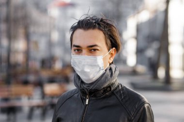 Koruyucu maskeli bir adam karantina şehrinde yürüyor. Güvenlik maskesi takan beyaz bir adam. Koronavirüs kavramı. Hastalık salgını