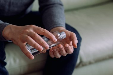 Coronavirus. Tıbbi dezenfektan jeli kullanan, evde dizüstü bilgisayarda çalışan tanınmayan bir adamı kapatın. Coronavirus için karantinada küçük bir şirket dezenfektan jeliyle çalışıyor. Seçici odak.
