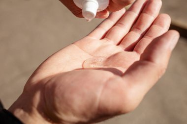 Virüs salgınını önlemek için avuç içine küçük taşınabilir antibakteriyel el dezenfektanı kullanan bir adamın görüntüsünü kapat. Dezenfekte eden eller. Ellerini düzgün bir şekilde temizleyip dezenfekte etmek..