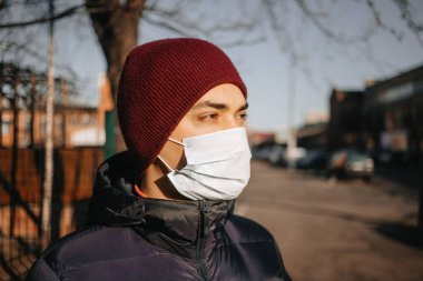 Koronavirüs hastalığına karşı koruyucu maske takan genç bir adam. Yüzünde tıbbi maske olan bir adamın yakın plan portresi. Karantina önlemleri. Salgın Koronavirüs COVID-19.