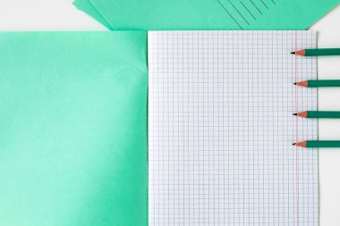 Masada kafeste açık bir defter var. Kalemler okul defterinin yanında. Okul için Not Defteri