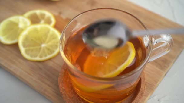 男はレモンとお茶を攪拌し、それの隣にスプーンを置く.免疫回復ドリンク — ストック動画