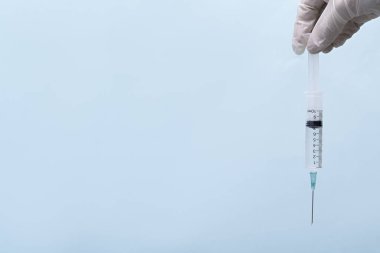 Mavi arka planda iğnesi olan bir şırınga. Akut tıbbi iğne. Hemşire şırınga tutuyor.