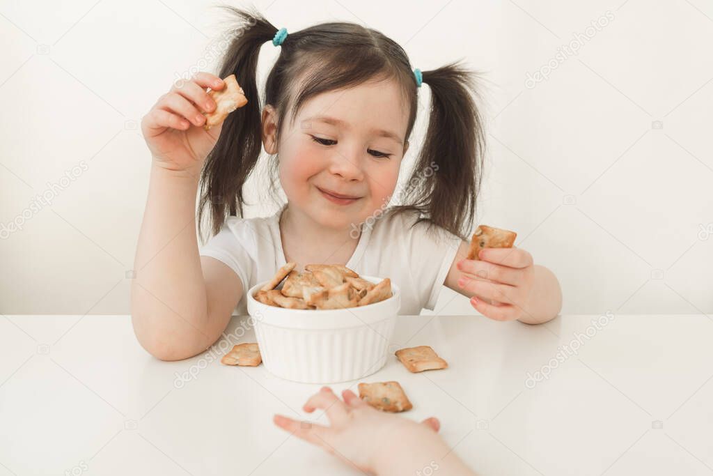 Children eat gluten cookies. A baby eats delicious pastries. Baby handles grab a cookie