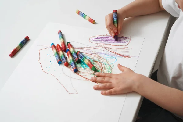 Dziecko rysuje kredkami woskowymi na papierze. Zbliżenie procesu kreatywności dzieci. Rozwój zdolności twórczych od dzieciństwa — Zdjęcie stockowe