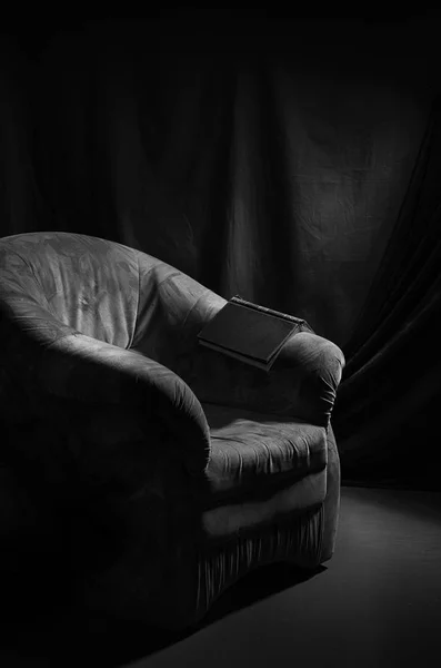 Stary fotel i książkę w ciemnym pokoju. — Zdjęcie stockowe