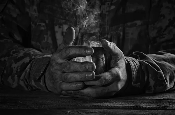 A mug of hot tea in the hands of a warrior. — Stock Photo, Image