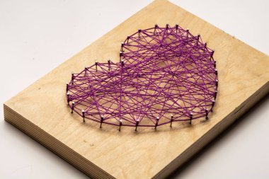 Kalp şeklinde çivilere sarılı iplikler.