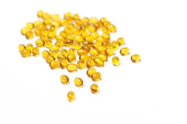 Beyaz arka planda bir sürü saydam sarı renkli tablet yatar. Yukarıdan görüntüle