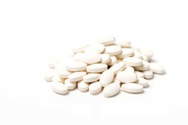 A pile of white oval-shaped tablets on white background. clipart