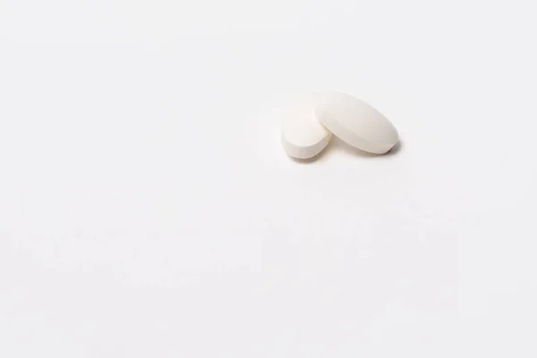 Twee Witte Ovale Tabletten Witte Achtergrond Een Ligt Bovenop Ander Stockafbeelding