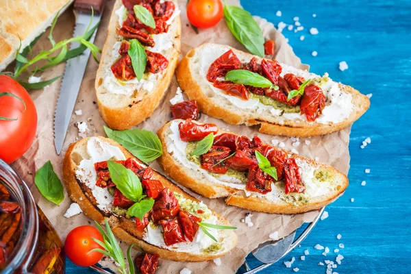 Bruschetta with cream cheese, pesto, fresh basil and sun dried t — Stock Photo, Image