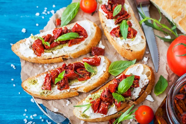 Bruschetta with cream cheese, pesto, fresh basil and sun dried t — Stock Photo, Image