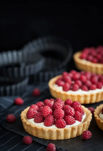 Deliciosas mini tortas de framboesa no fundo escuro — Fotografia de Stock