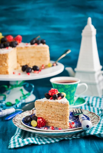 Kawałek ciasto miód ozdobione świeżymi owocami — Zdjęcie stockowe