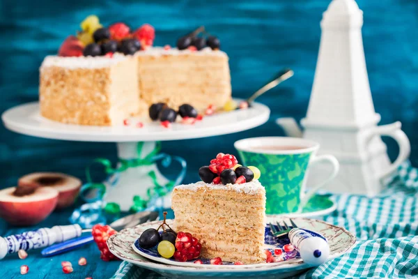 Stuk van zelfgemaakte honing taart gedecoreerd met vers fruit — Stockfoto