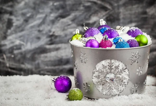 Christmas balls in snow covered bucket — Stock Photo, Image