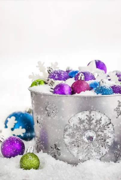 Christmas balls in snow covered bucket — Stock Photo, Image