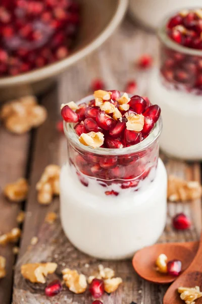 Fresh yogurt with pomegranate seeds and walnut in a glass jars — Stock Photo, Image