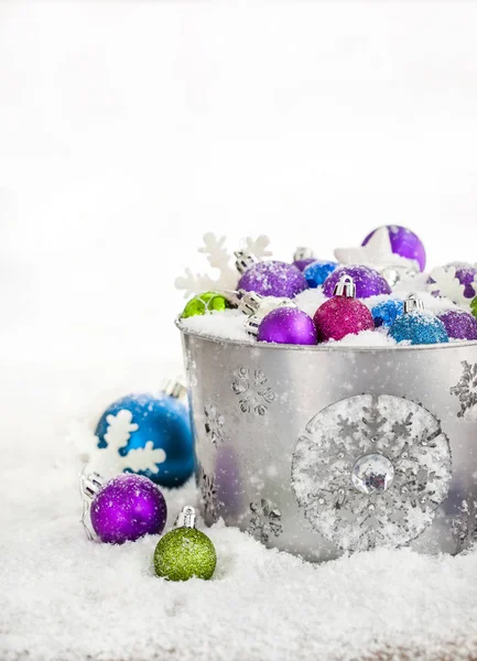 Christmas balls in snow covered bucket — Stock Photo, Image