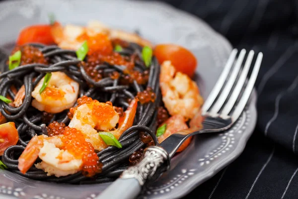 Černé špagety s krevetami a červeným kaviárem — Stock fotografie