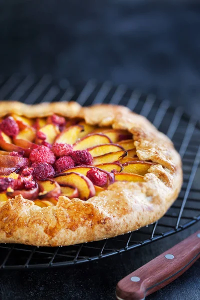 Galette aux pêches et framboises sur fond sombre — Photo