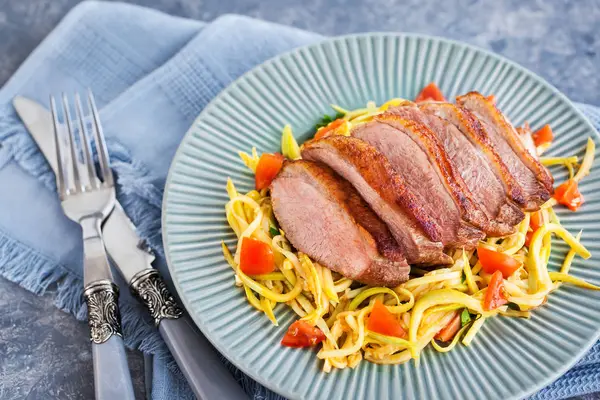 Poitrine de canard rôtie et nouilles aux courgettes aux tomates — Photo