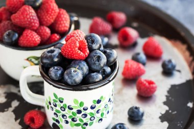 Olgun taze yaban mersini ve kupalar içinde ahududu 