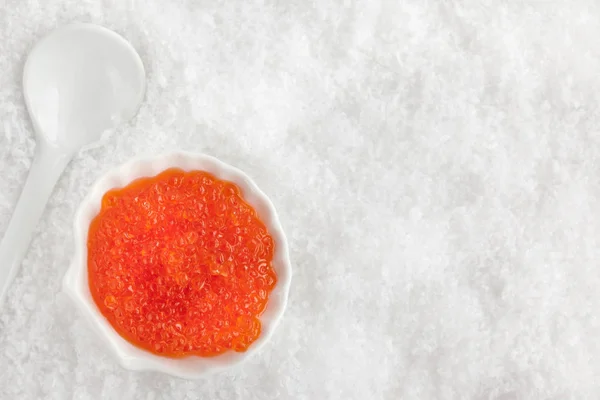 Delicious red caviar in bowl on white snow background — Stock Photo, Image