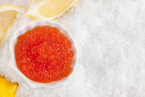 Delicious red caviar in bowl on white snow background — Stock Photo, Image