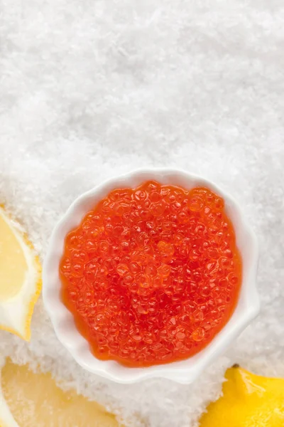 Delicious red caviar in bowl on white snow background — Stock Photo, Image