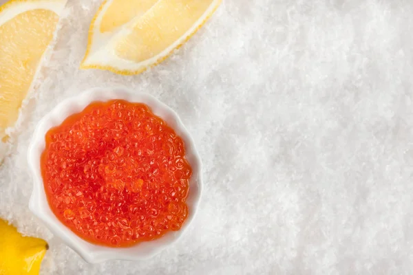 Delicious red caviar in bowl on white snow background — Stock Photo, Image