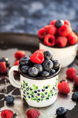 Olgun taze yaban mersini ve kupalar içinde ahududu 