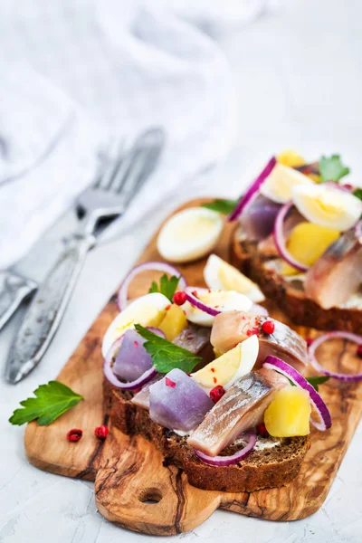 Открытый сэндвич (сморреброд) с сельдью, луком, картошкой и яйцами — стоковое фото