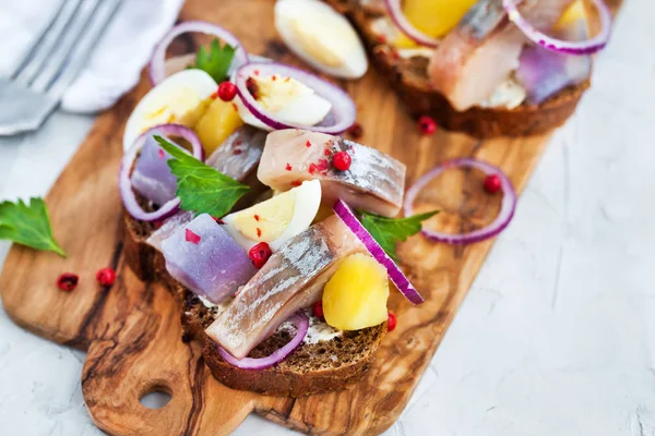 Открытый сэндвич (сморреброд) с сельдью, луком, картошкой и яйцами — стоковое фото