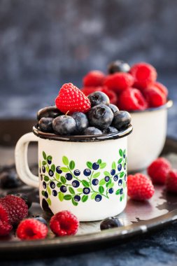 Olgun taze yaban mersini ve kupalar içinde ahududu 