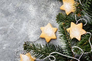 Chrismtas kurabiye yıldızları ve gri arkaplanda köknar ağacı dalları,