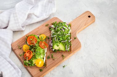 Avocado rye toasts with green herbs, onion and cherry tomatoes, 