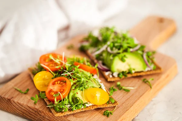 Avocado rye toasts with green herbs, onion and cherry tomatoes, — Stock Photo, Image