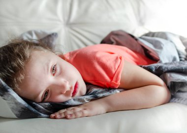 Hasta kız evdeki kanepede yatıyor. Üzgün ruh hali, yalnız çocuk ve karantina konsepti.