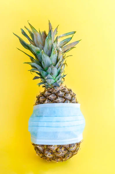 Pineapple wearing surgical medical mask on yellow background. Coronavirus, allergy, safety summer concept — Stock Photo, Image