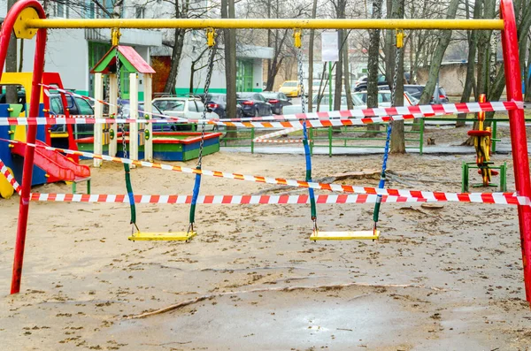 Pandemia de Coronavirus y distanciamiento social, los niños cerrados oscilan con cinta de señal en el patio de recreo al aire libre Moscú Rusia — Foto de Stock